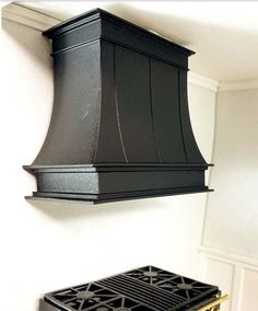 a black range hood hanging from the side of a wall above a stove top oven