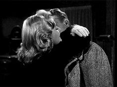 a man kissing a woman on the cheek in a black and white photo by mirror