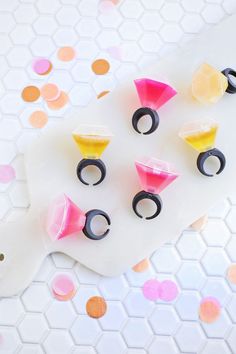 several different colored plastic rings on top of a white board with confetti sprinkles