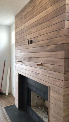 an empty living room with a fireplace and wood paneling on the wall behind it