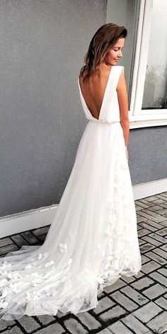 a woman standing in front of a window wearing a white dress with flowers on it