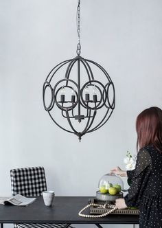 a woman sitting at a table in front of a chandelier hanging from the ceiling