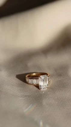 an engagement ring with two baguettes on it sitting on top of a white cloth