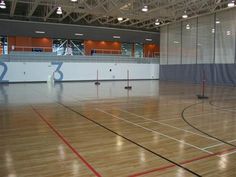 an indoor basketball court with no people on it and several poles in the middle of the floor