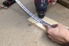 a man is using a drill to measure the length of a piece of wood with a measuring tape