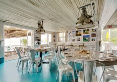 the inside of a restaurant with blue flooring and white tables, chairs and lamps