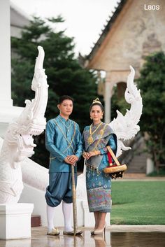 two people standing next to each other in front of a statue