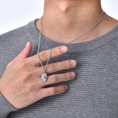 a man wearing a silver necklace with a diamond pendant on it's left hand