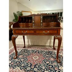 an antique desk with two drawers and a rug on the floor in front of it