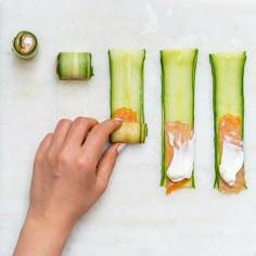 someone is making sushi rolls with cucumbers and sauces on the side