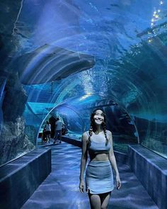 a woman is walking through an underwater tunnel