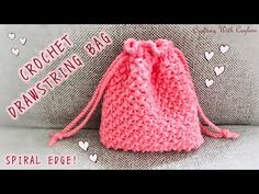 a pink crochet drawstring bag sitting on top of a couch