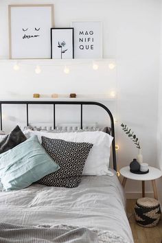 a bed with white sheets and pillows next to two framed pictures on the wall above it