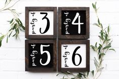 three wooden blocks with numbers on them sitting next to a plant and brick wall in the background