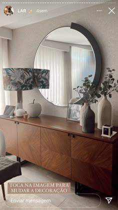 a large round mirror sitting on top of a wooden dresser next to a vase filled with flowers