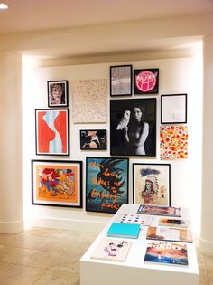 a room filled with lots of art and pictures on the wall next to a white table