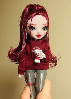 a hand holding a doll with red hair