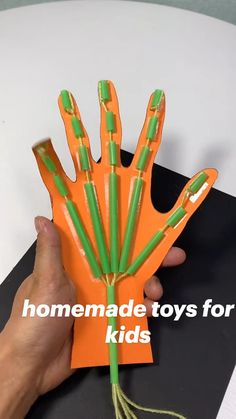 a hand holding an orange and green toy with the words homemade toys for kids on it