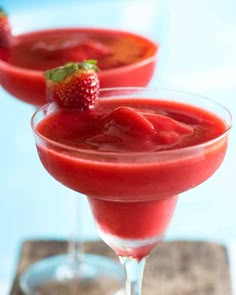 two martini glasses filled with strawberry juice and garnished with fresh strawberries on the rim