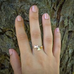 a woman's hand with a gold ring on top of it and a tree in the background