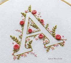 a cross stitch pattern with pink flowers and green leaves in the shape of a letter