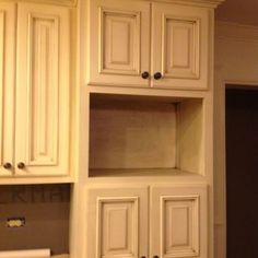 the kitchen cabinets are all white and have wood trimmings on them, but no one is in it