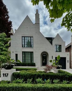 a large white house surrounded by hedges and trees