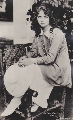 an old black and white photo of a woman sitting on a chair