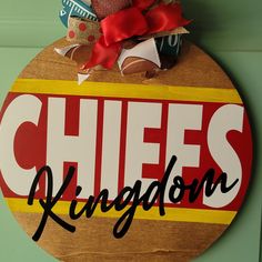 a wooden sign that says chiefs kingdom hanging on a door with a teddy bear in it