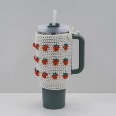 a crocheted coffee cup with strawberries on it and a handle is shown