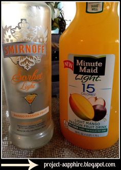 two bottles of drink sitting next to each other on top of a cloth covered table