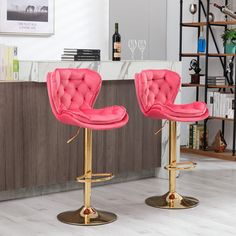 two pink velvet bar stools in front of a counter with wine glasses on it