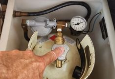 a man is pointing at the pressure gauge on a water heater's tank