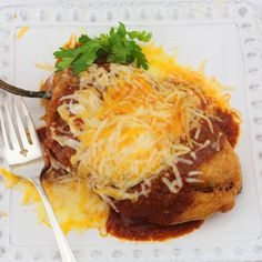 a white plate topped with meat covered in cheese and gravy next to a fork