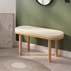 a wooden bench sitting in front of a green wall with a round mirror on it