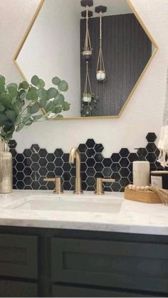 a bathroom with black and white tiles, gold accents and a mirror over the sink