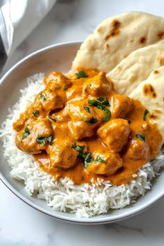 a white plate topped with rice and meat covered in gravy next to pita bread