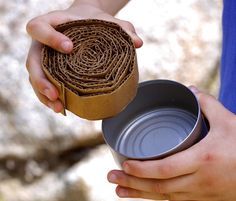 a person holding a can and a roll of brown paper in their hands, with the lid open