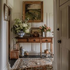 a room with a table, vases and pictures on the wall next to it