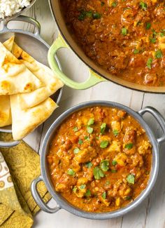 two pans filled with curry and pita bread