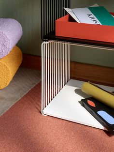 three different colored towels are sitting on the floor next to a table with two books