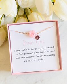 a card with a pink rose on it sitting next to some white flowers and a flower bouquet