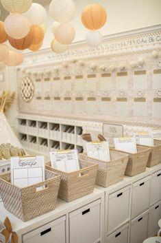 several baskets are lined up on the counter in front of many paper lanterns hanging from the ceiling