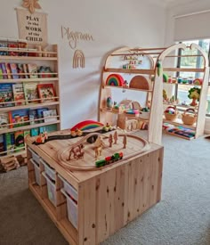 there is a wooden toy train set on display in the playroom with bookshelves and toys