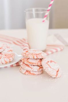 a stack of cookies next to a glass of milk on top of a white table