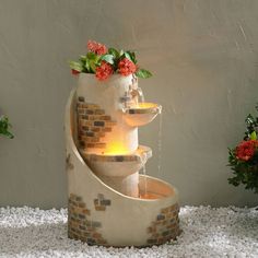 there is a fountain made out of bricks with flowers in the center and water running down it