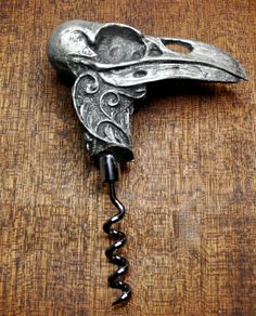 a metal bird head hanging from a hook on a wooden table with a key in it's mouth