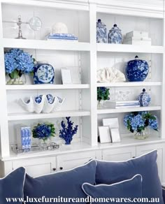 a blue and white living room with bookshelves filled with vases, plates and flowers