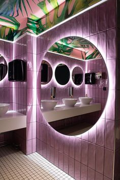 a bathroom with three sinks, mirrors and lights on the wall above them are palm leaves painted on the walls