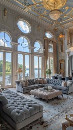 a large living room with high ceilings and lots of windows on the wall, along with couches and chairs